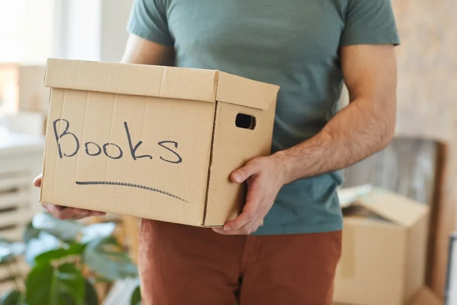 Books being packed into a cardboard moving box