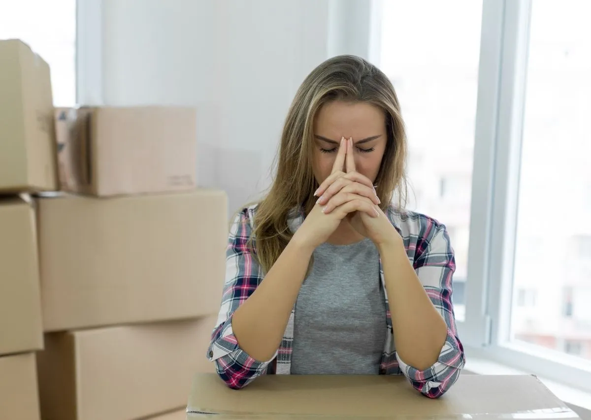 Person surrounded by stacked moving boxes during a stressful move