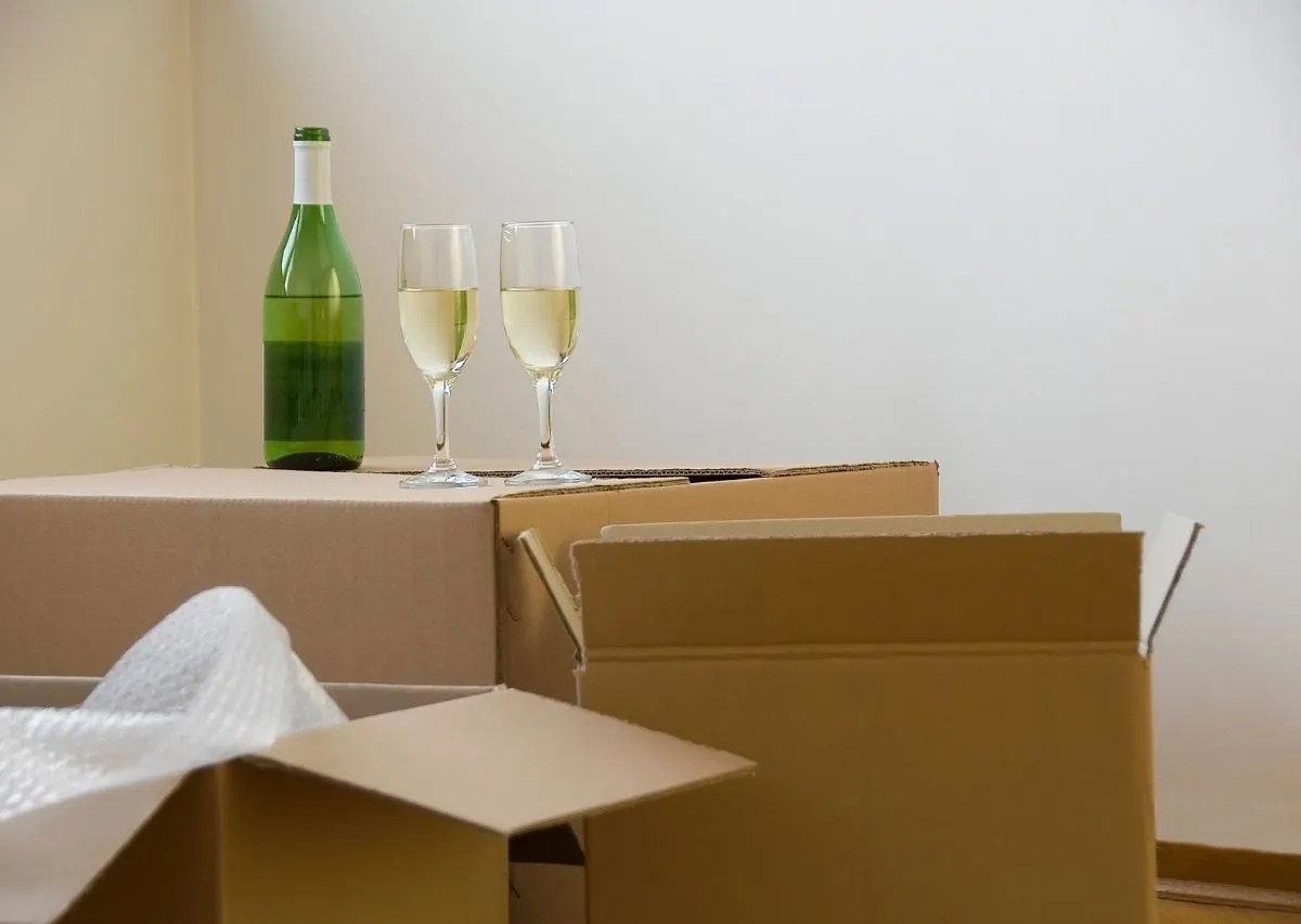 Wine glasses being wrapped in packing paper and placed in a moving box