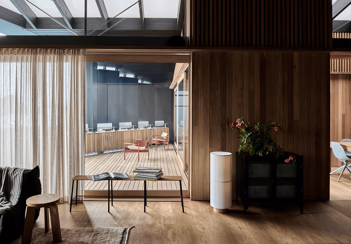 Modern wooden interior with glass door to deck, chairs, table, and plant.