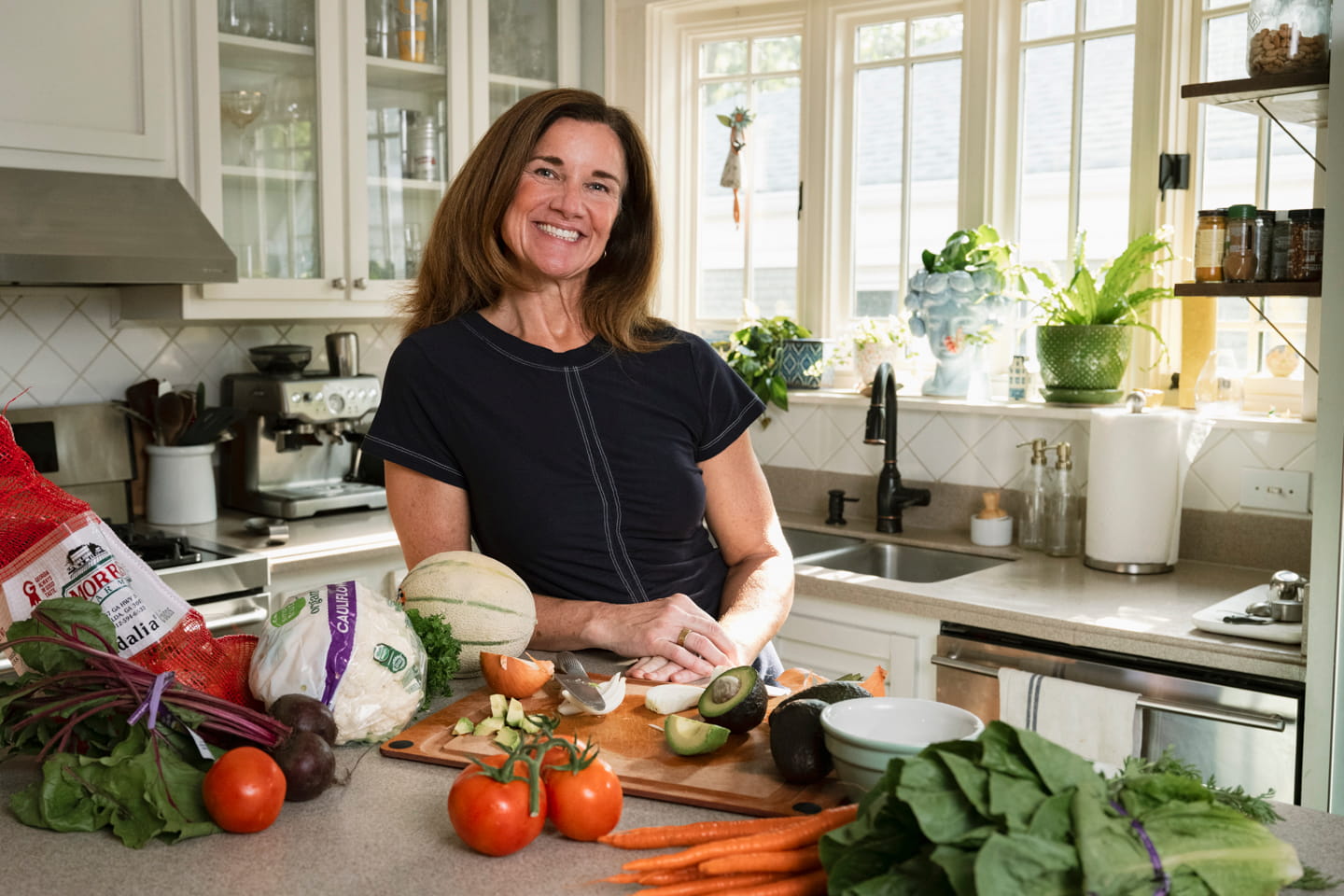 Surrounded by fresh vegetables, a woman prepares to cook a healthy meal.