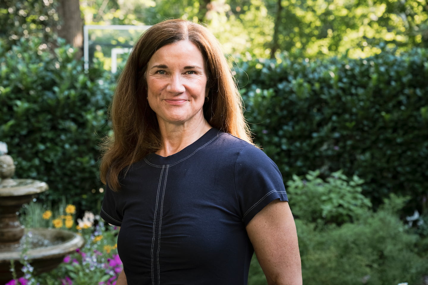 A woman softly smiles in the garden.