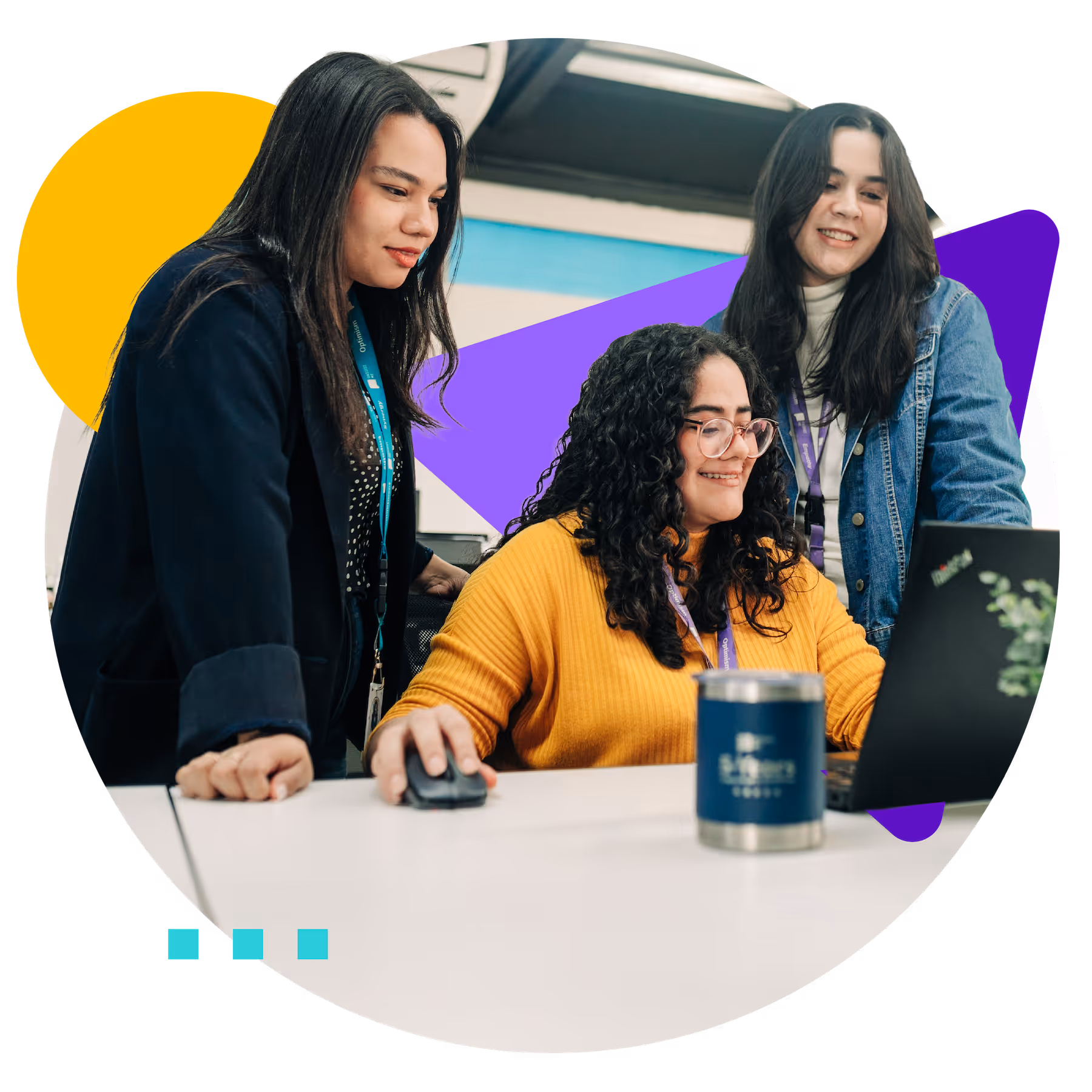Three women collaborating and smiling while working on a laptop at a desk.