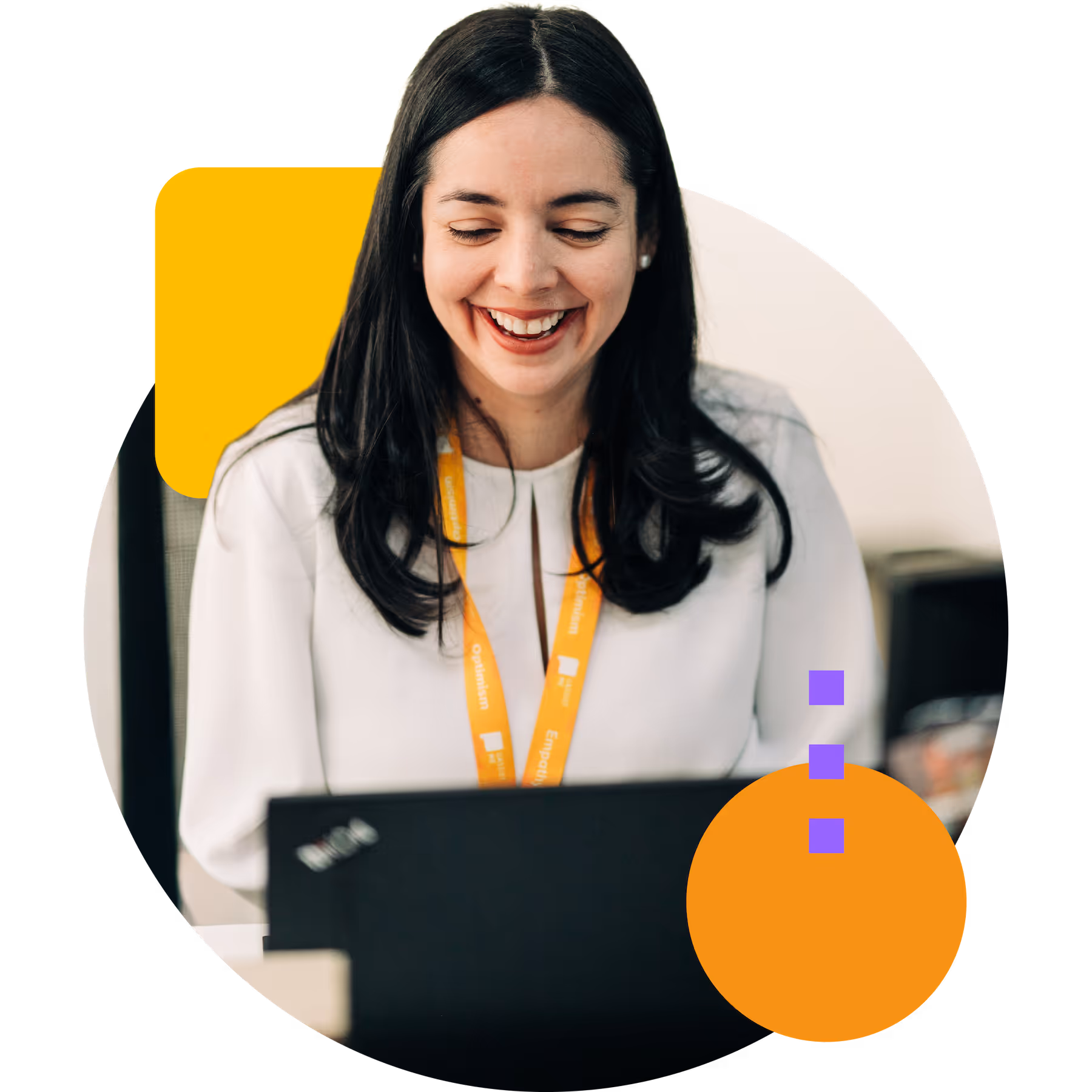 Smiling woman with long dark hair wearing a white blouse and yellow lanyard, looking at a laptop.