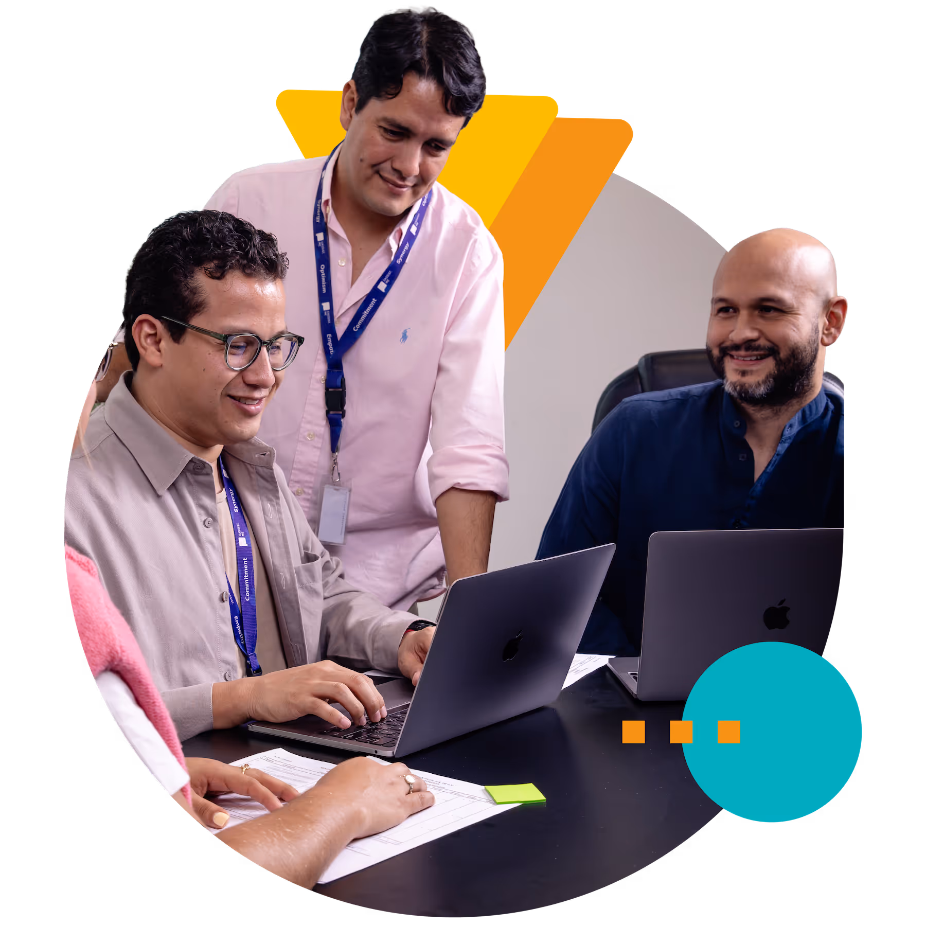 Three professionals collaborating at a table with laptops and documents, smiling and engaged in discussion.