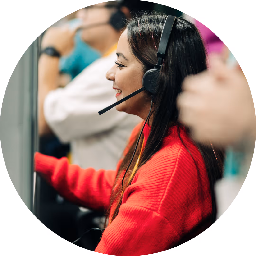 Smiling woman wearing headset and red sweater working at a call center.