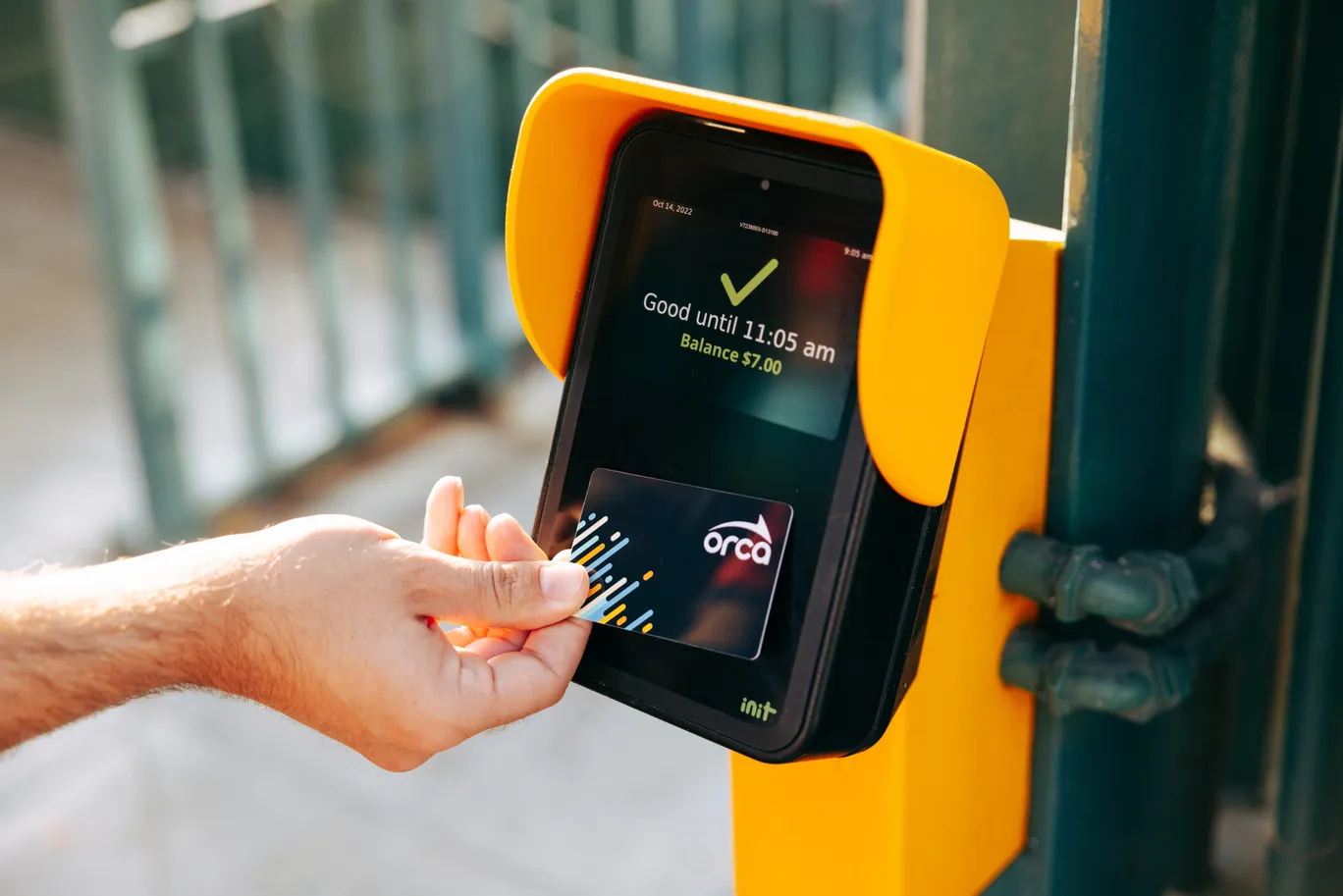 Person scanning an ORCA card at a yellow transit card reader.