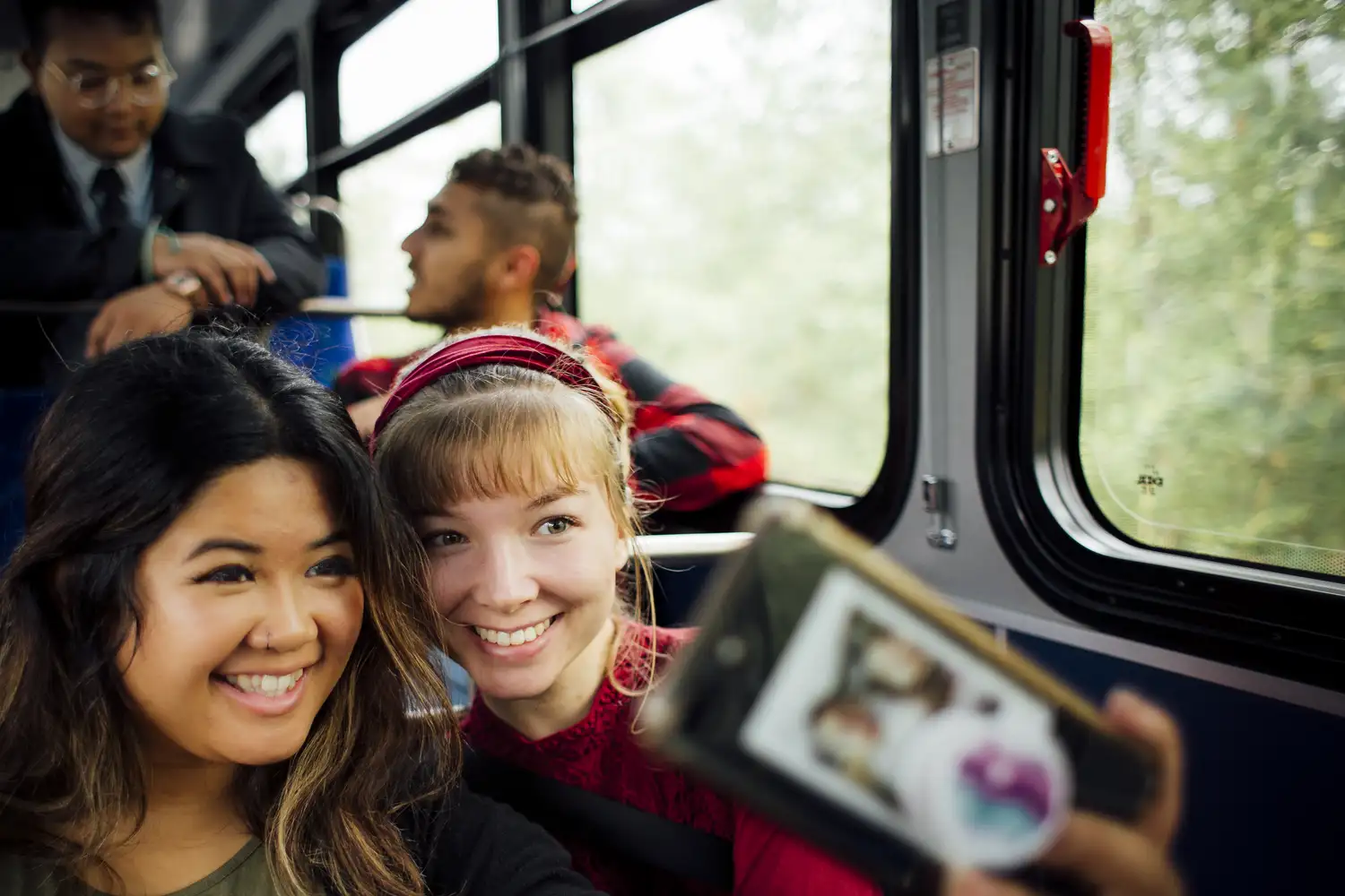 Two riders smile for a selfie on a bus