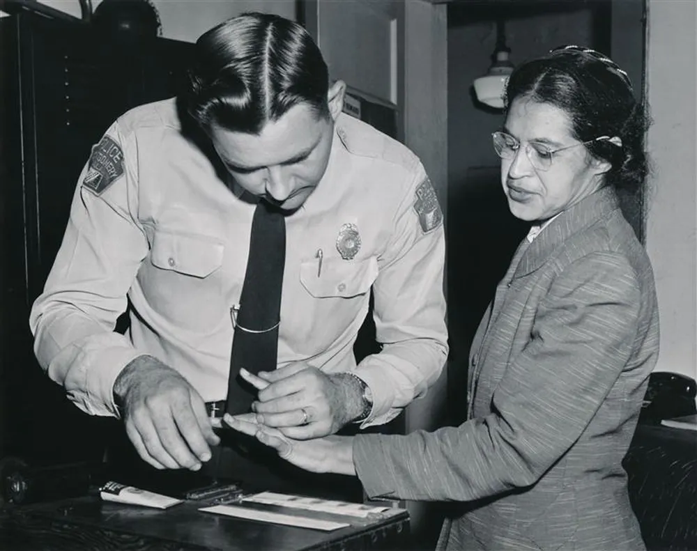 Rosa Parks being fingerprinted by police officer.