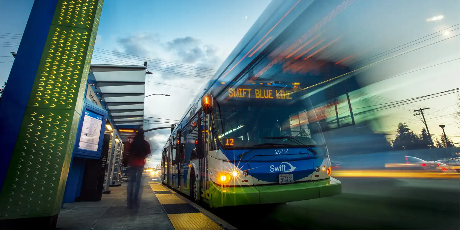 a Swift bus at a station at dusk