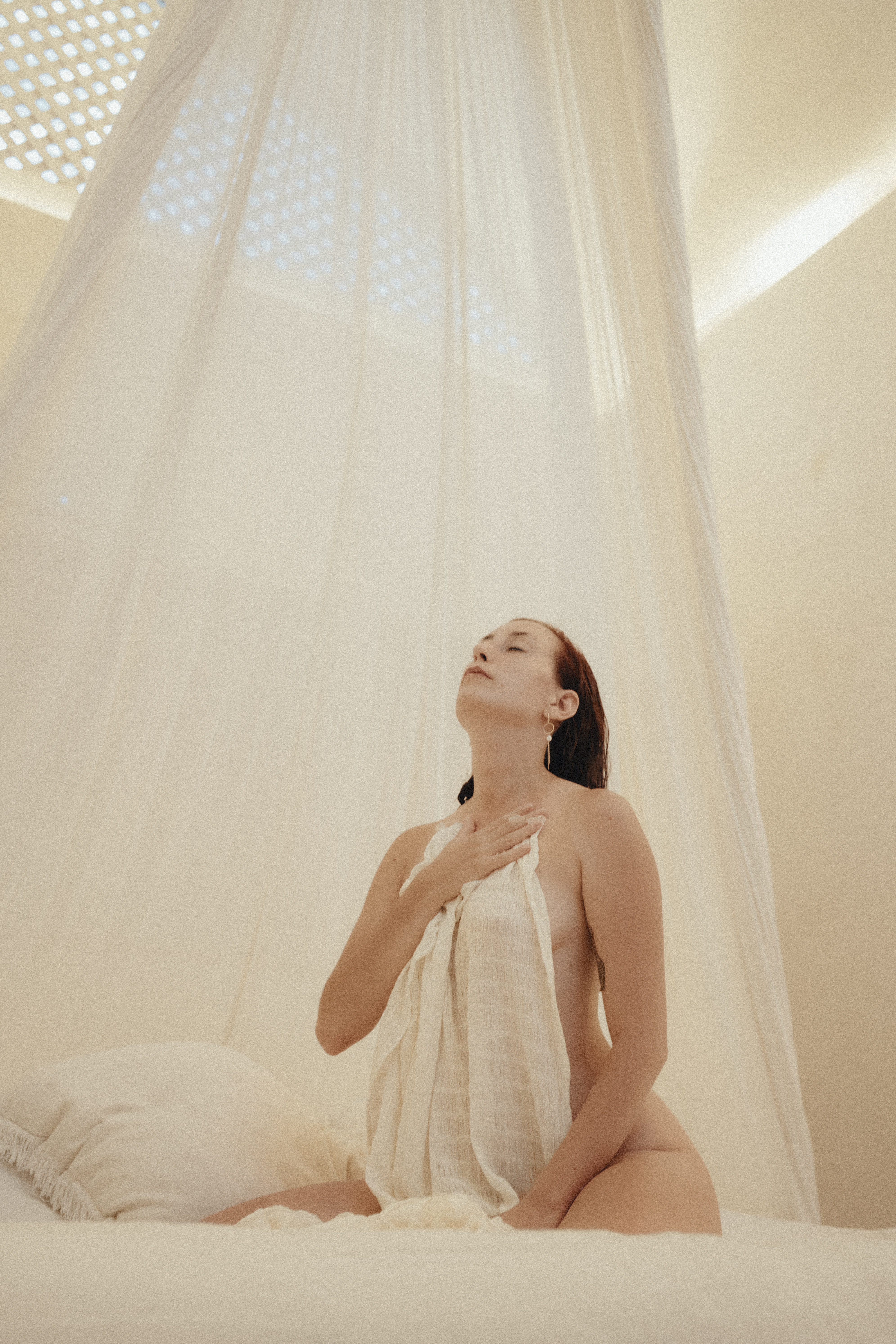 Delfina seated beneath a canopy of soft white fabric
