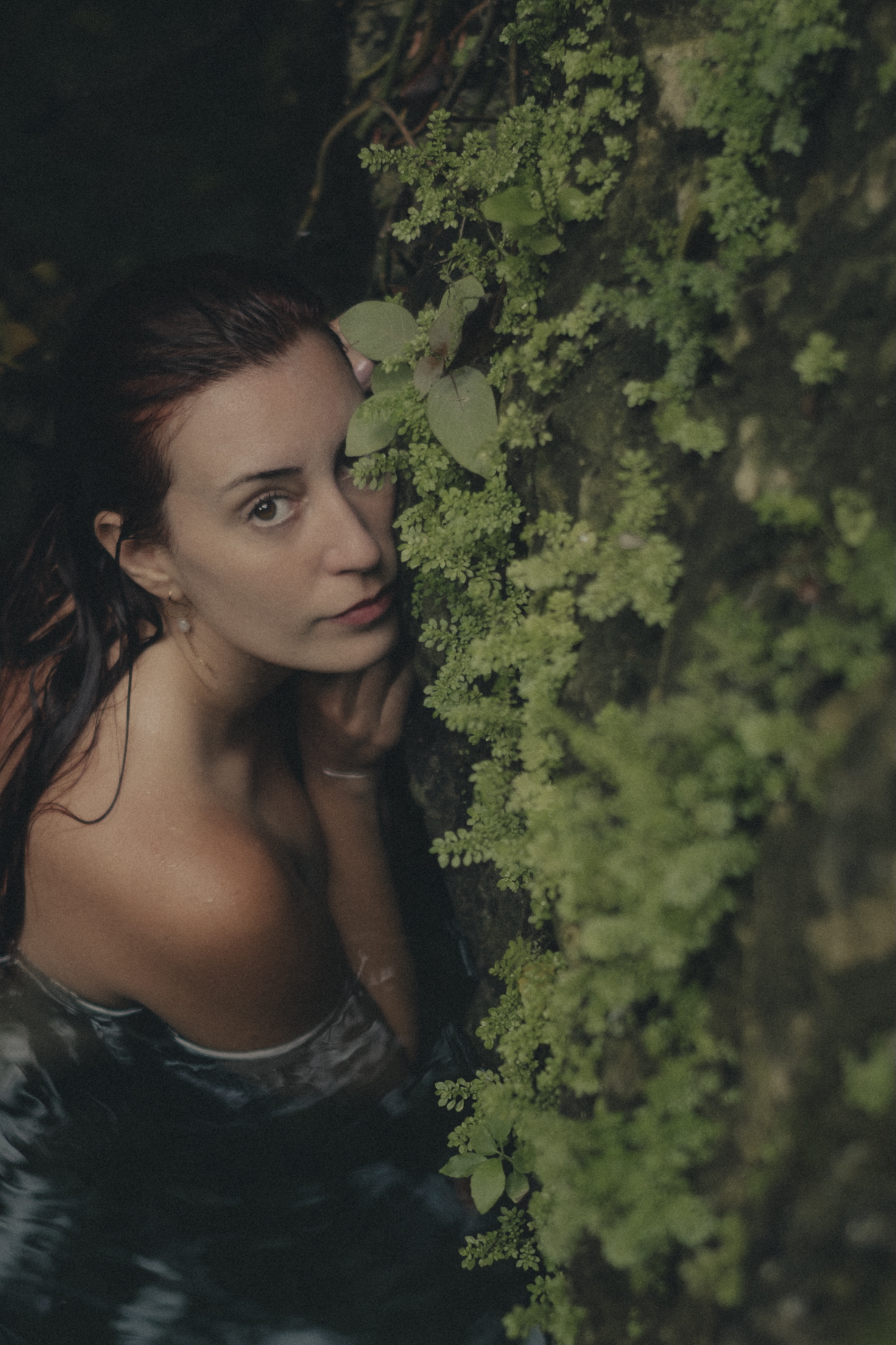 Delfina beside a moss-covered rock wall