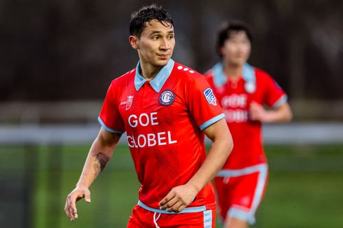 Male soccer player in red and blue uniform with 'GOE GLOBEL' on the jersey looking to the side on the field.