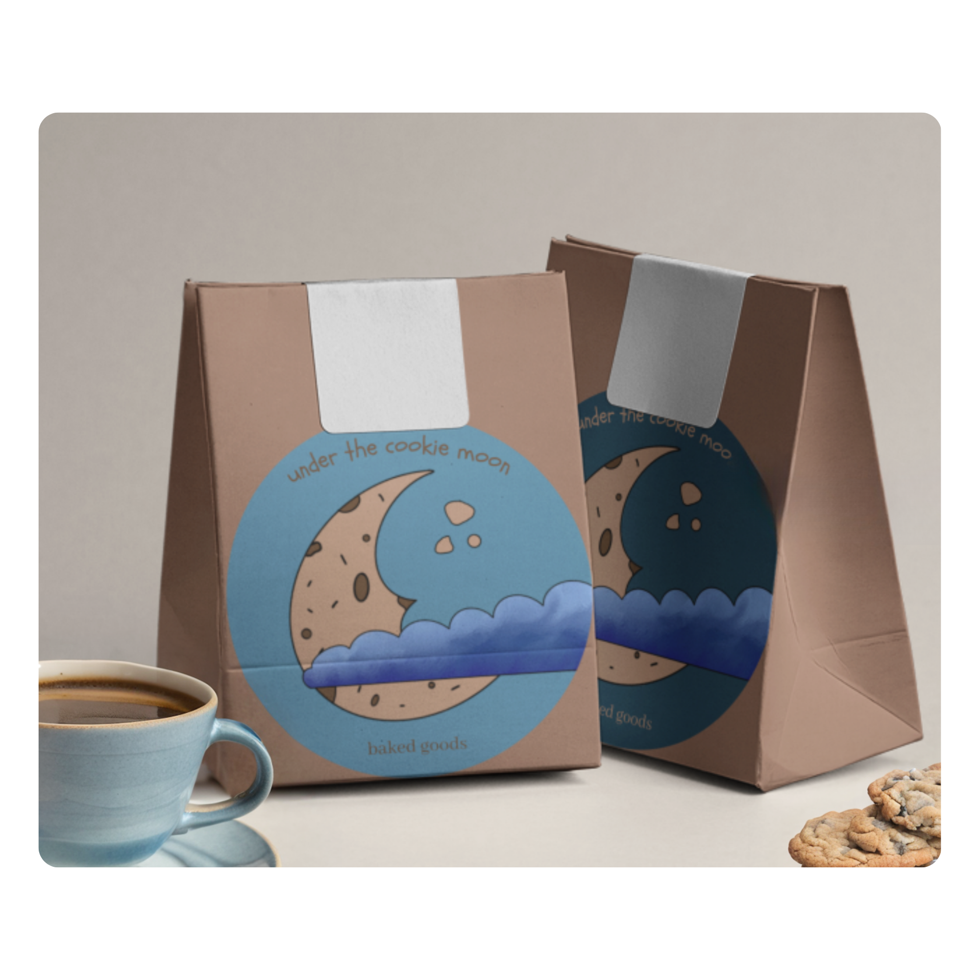 Packaging design for Under the Cookie Moon bakery, featuring two brown paper bags with a whimsical logo of a crescent moon shaped like a chocolate chip cookie, set against a blue sky with fluffy clouds. The branding evokes a cozy, handcrafted feel, complementing the home-baked treats inside. The image also includes a cup of coffee and a stack of freshly baked cookies, reinforcing the warm, inviting atmosphere of the brand.
