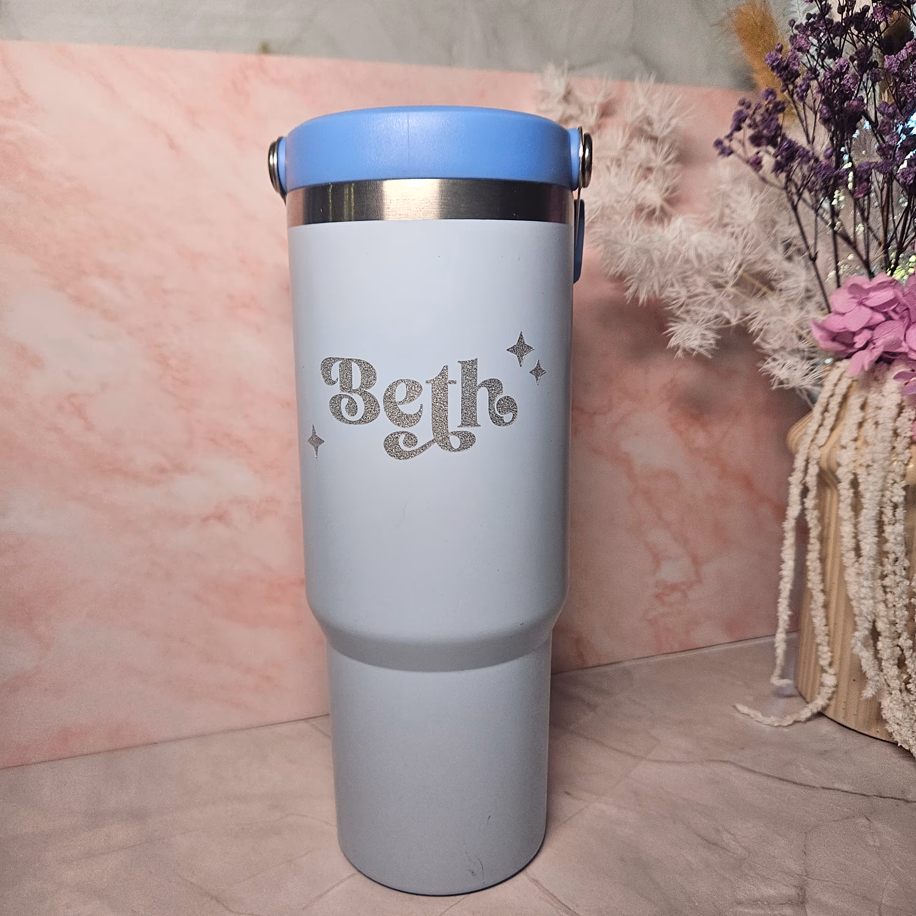 A blue tumbler with a silver decal that says Beth.
