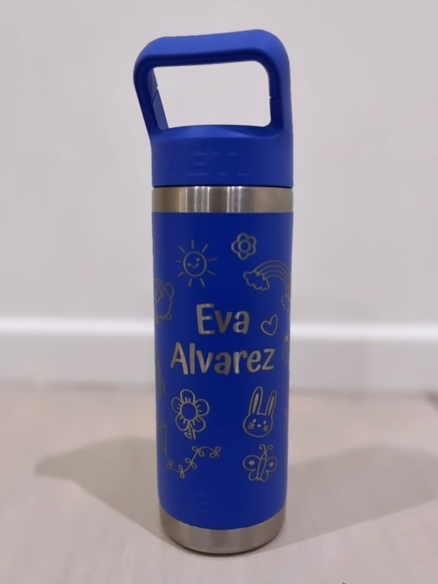 A purple Yeti water bottle engraved with a name and some children's doodles.