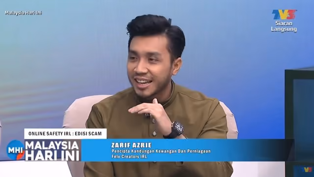 Man in brown shirt speaking during a Malaysia Hari Ini TV interview on online safety and scams.