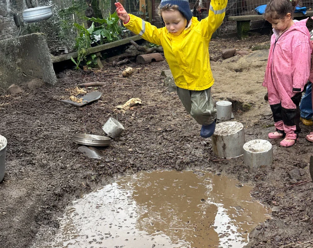 Children gently observing and touching a bird under teacher guidance, practicing empathy and care.