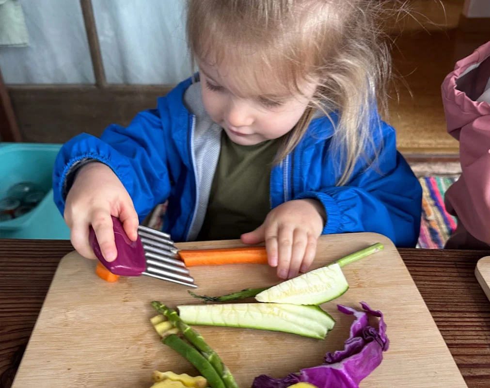 Child smiling while eating a colorful, home-cooked meal at Tree Sprites.