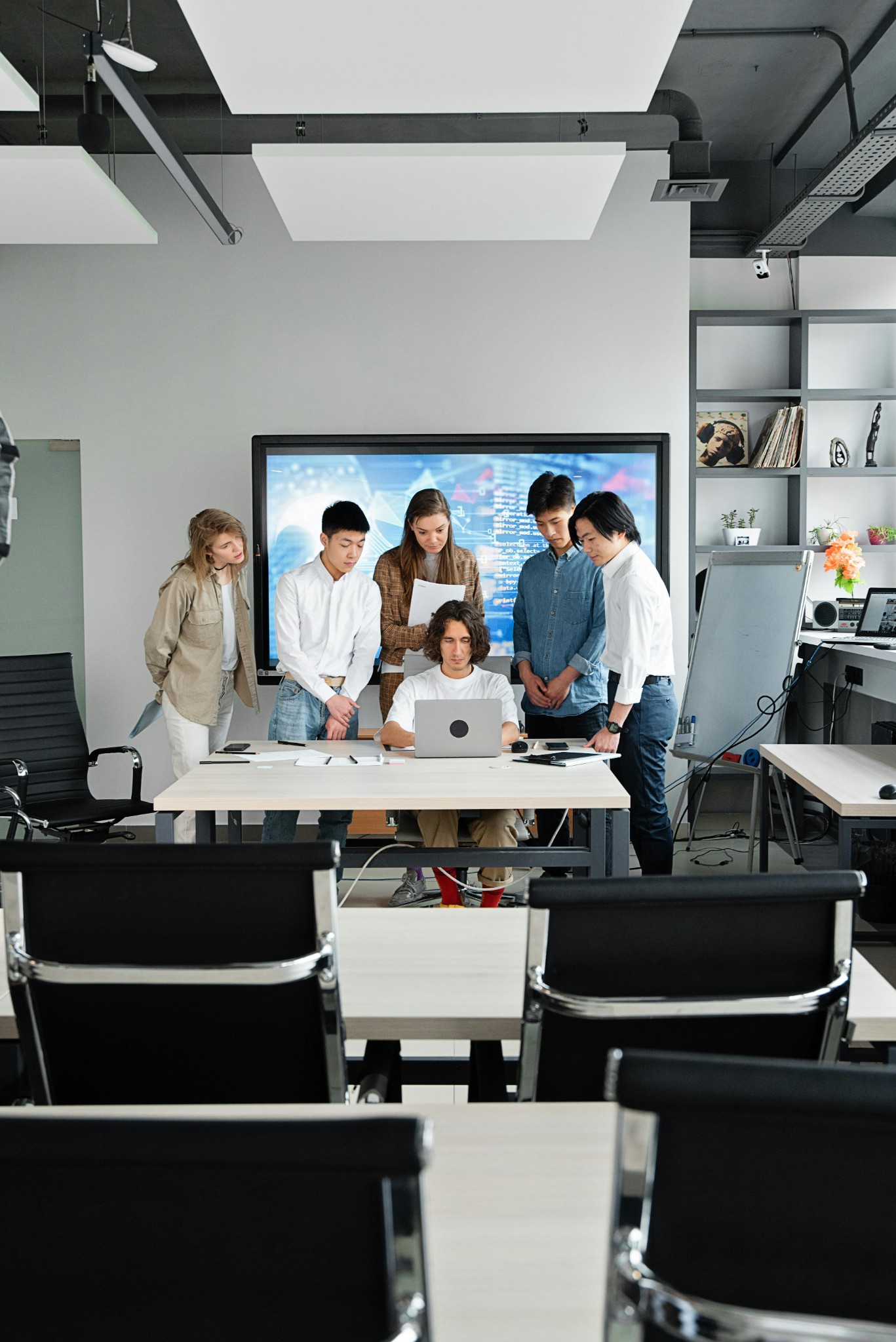Team gathered around laptop during presentation in modern conference room.