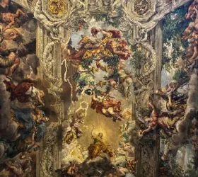 Ornate Baroque ceiling fresco with angels, cherubs, and mythological figures surrounded by intricate architectural details and clouds.