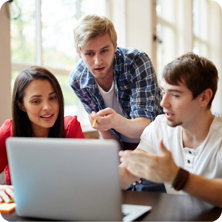 A woman and two men collaborate on a laptop, one man points at the screen.