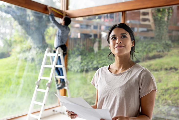 Cliente vérifiant son projet pendant qu’un artisan installe une structure en bois, symbole de confiance et transparence