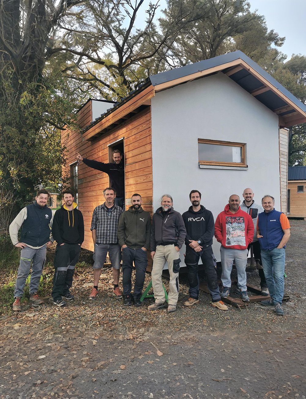 Équipe d’artisans du Réseau des Bâtisseurs devant une tiny house en bois écologique