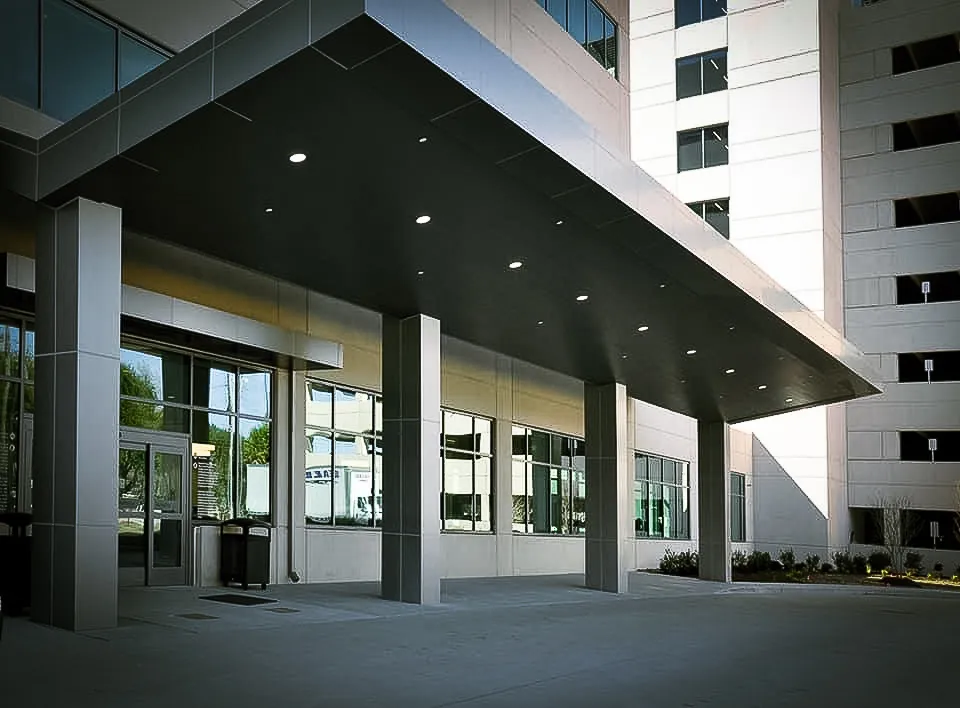 Commercial building exterior with glass windows, modern shades, and architectural signs