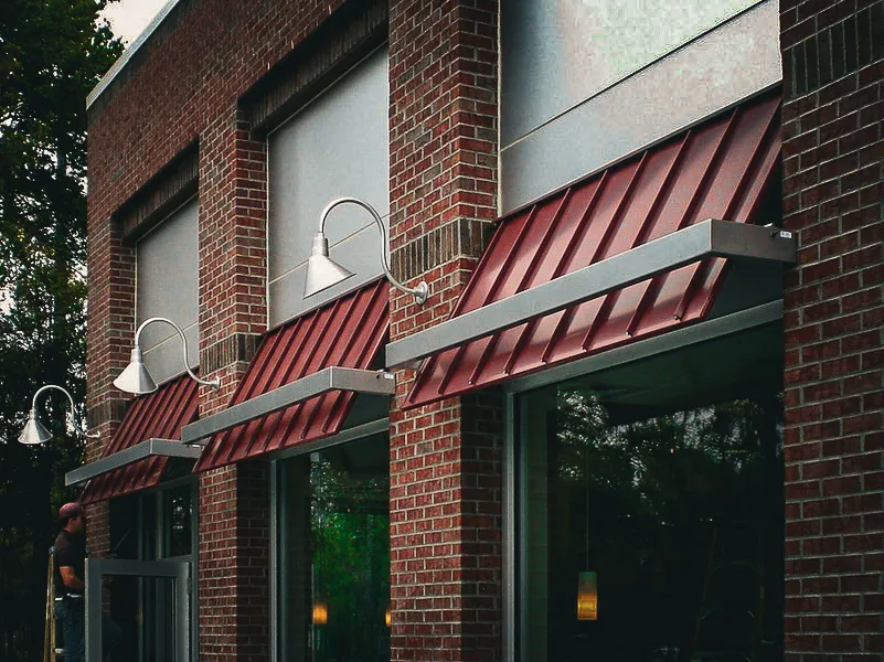 Commercial exterior with red awnings, signs, and shades on brick building