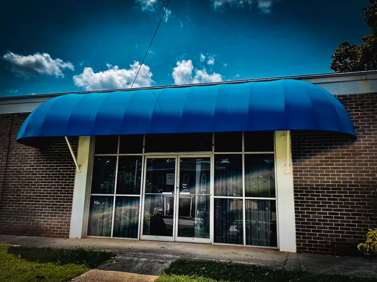 Commercial exterior with blue awning, brick walls, and large glass storefront signs