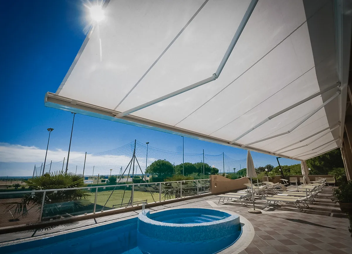 Commercial exterior with pool, awnings, shades, and signs near sports field