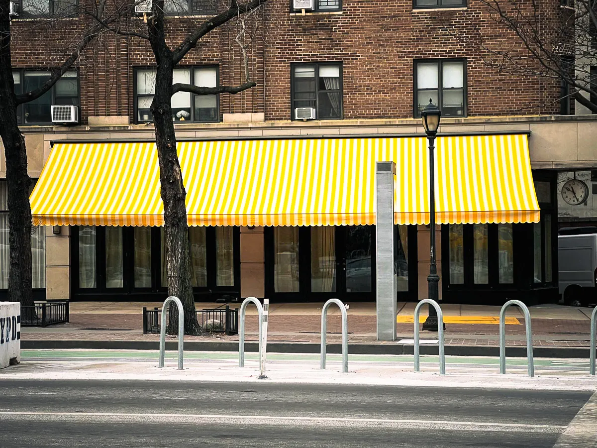 Martino Signs storefront with yellow and white striped awnings on brick building