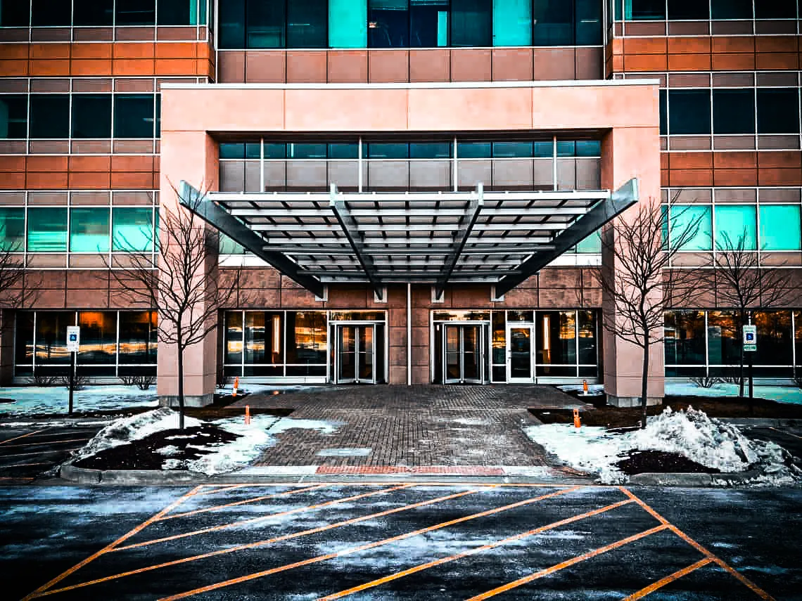 Commercial building exterior with modern glass entrance, awnings, and winter parking signs