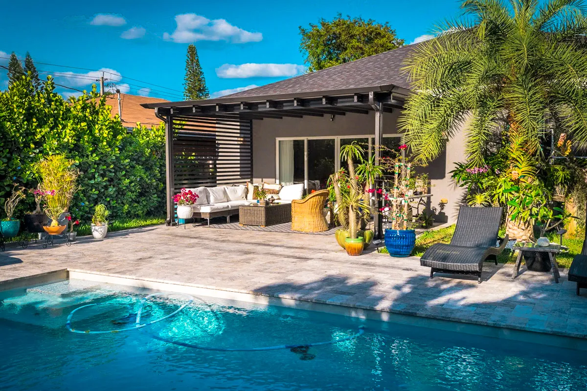 Commercial exterior patio with pool, shades, awnings, and lush tropical landscaping