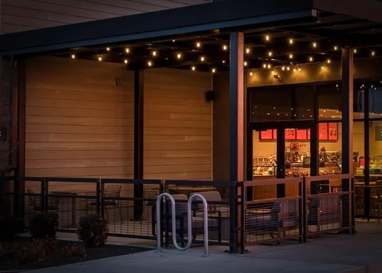 Commercial exterior with warm string lights, awnings, and shaded storefront entrance