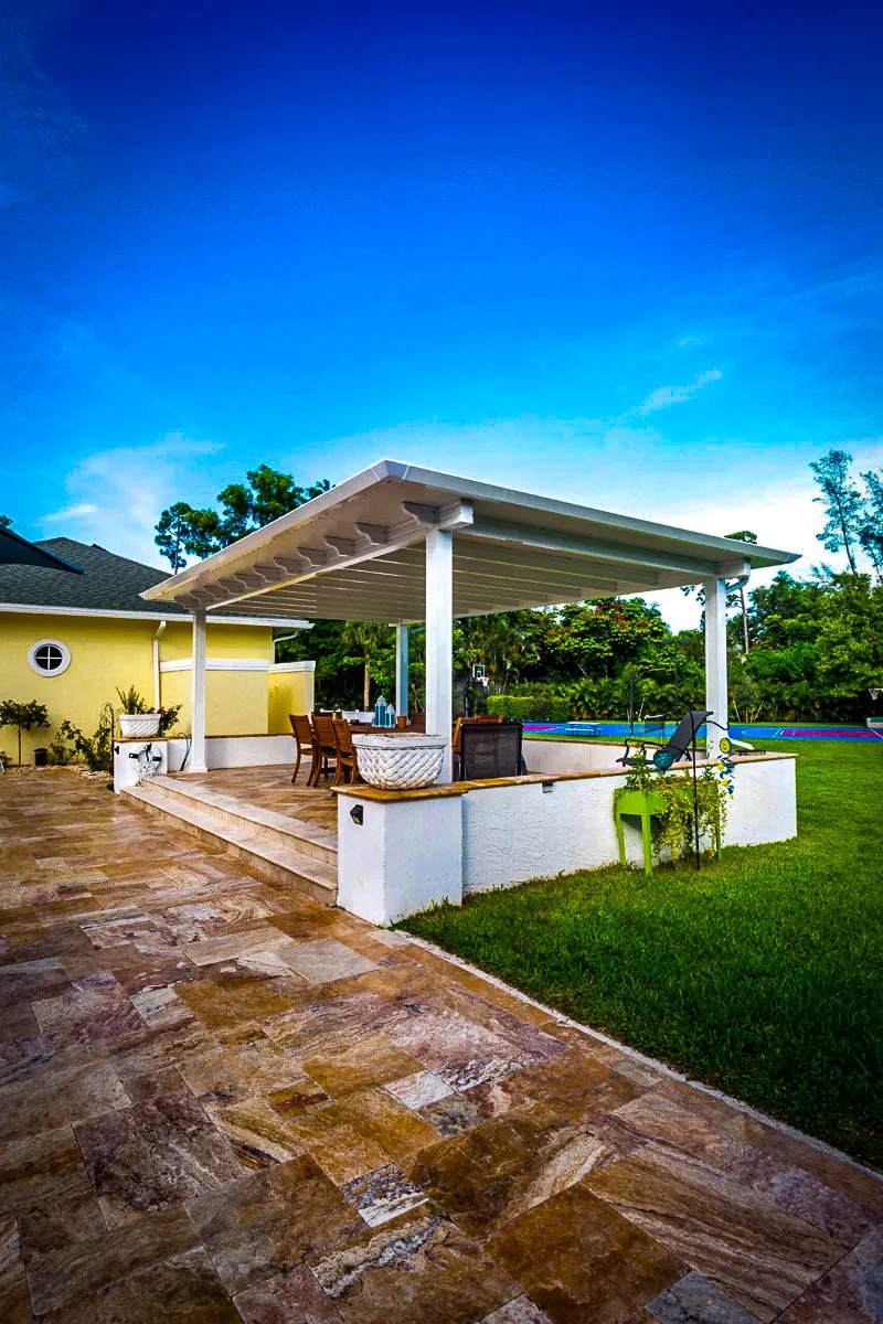 Commercial exterior with shaded patio, awnings, and stone flooring near pool