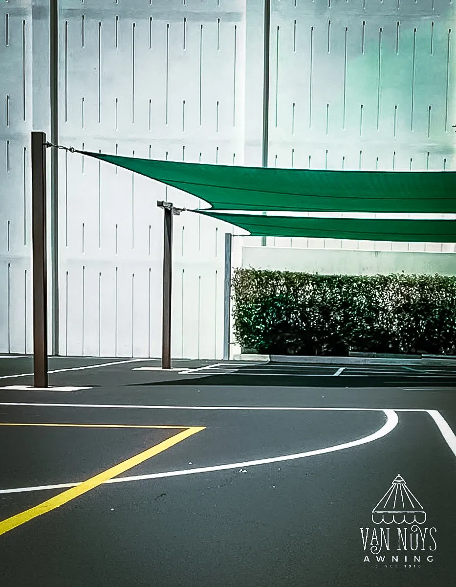 Commercial exterior with green shade sails, parking area, and architectural signs