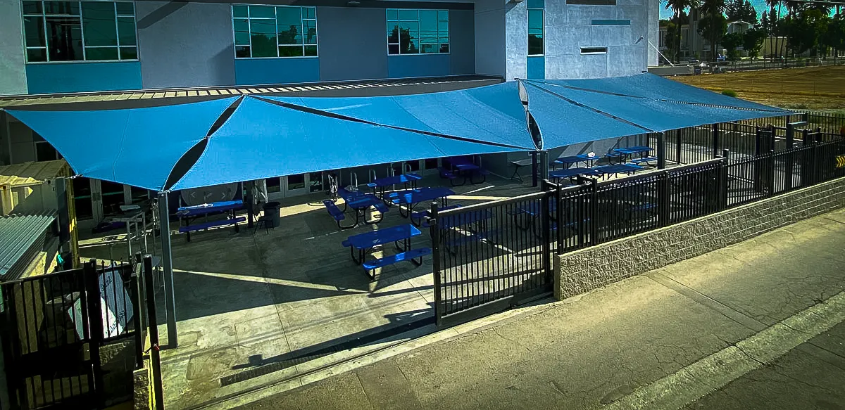 Commercial exterior with blue shade awnings and fenced seating area