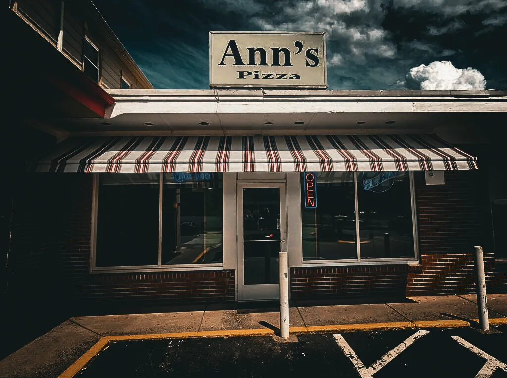 Commercial exterior of Ann's Pizza with striped awning and open sign