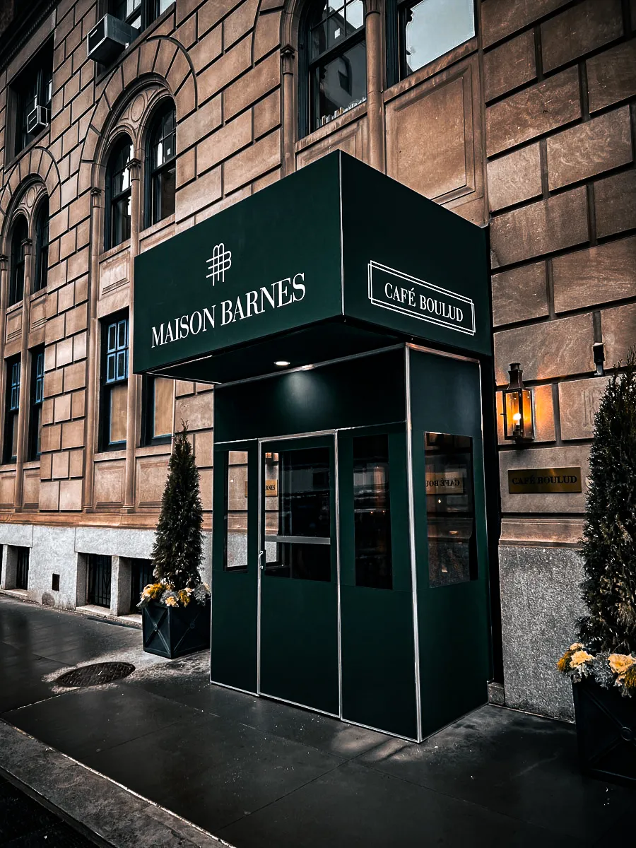 Commercial exterior with Maison Barnes and Cafe Boulud signs, awnings, shades