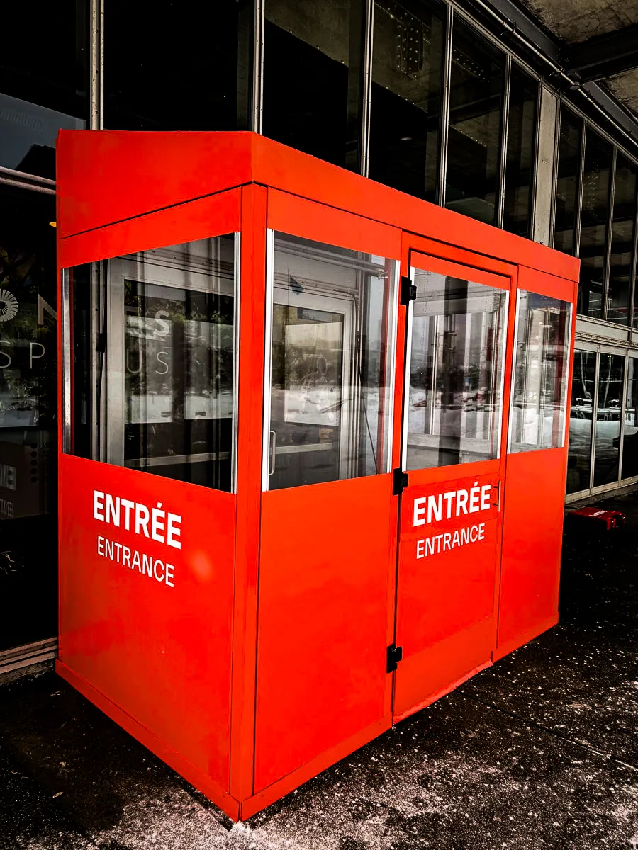 Commercial exterior entrance booth with bilingual signs and glass shades
