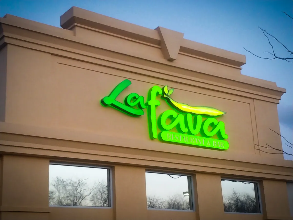 Commercial exterior with bright green La Fava Restaurant and Bar signs, windows, shades