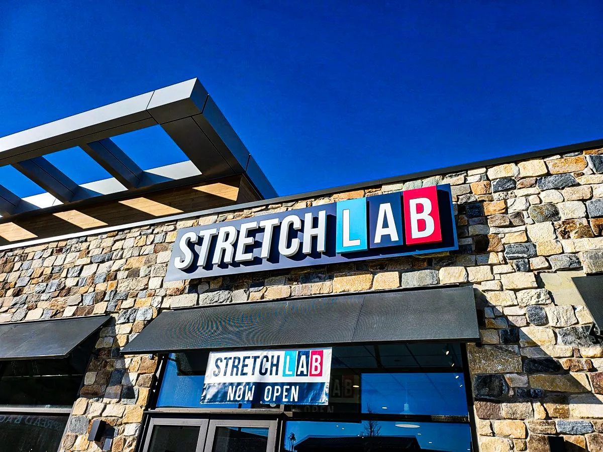 Commercial exterior with stone walls, StretchLab signs, awnings, and shades