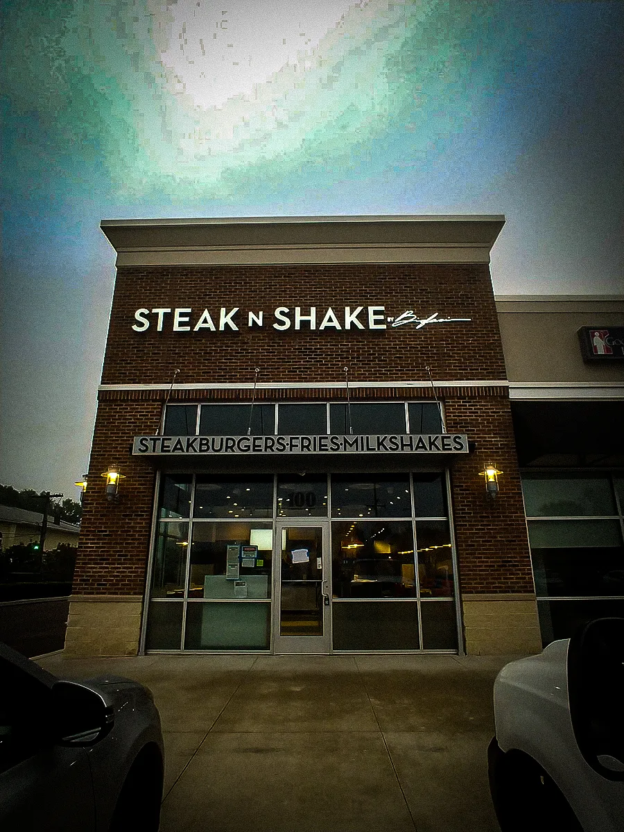 Commercial exterior with Steak n Shake signs, awnings, and shades at dusk