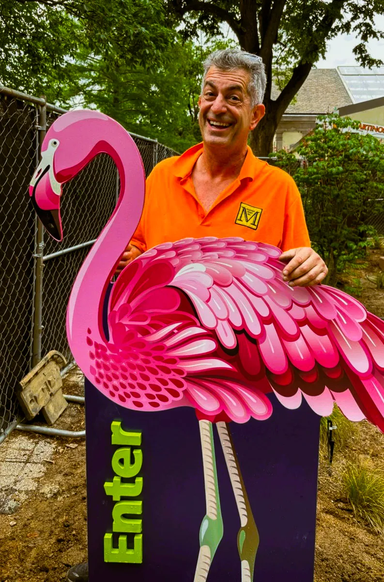Commercial exterior signage with vibrant pink flamingo display and smiling worker