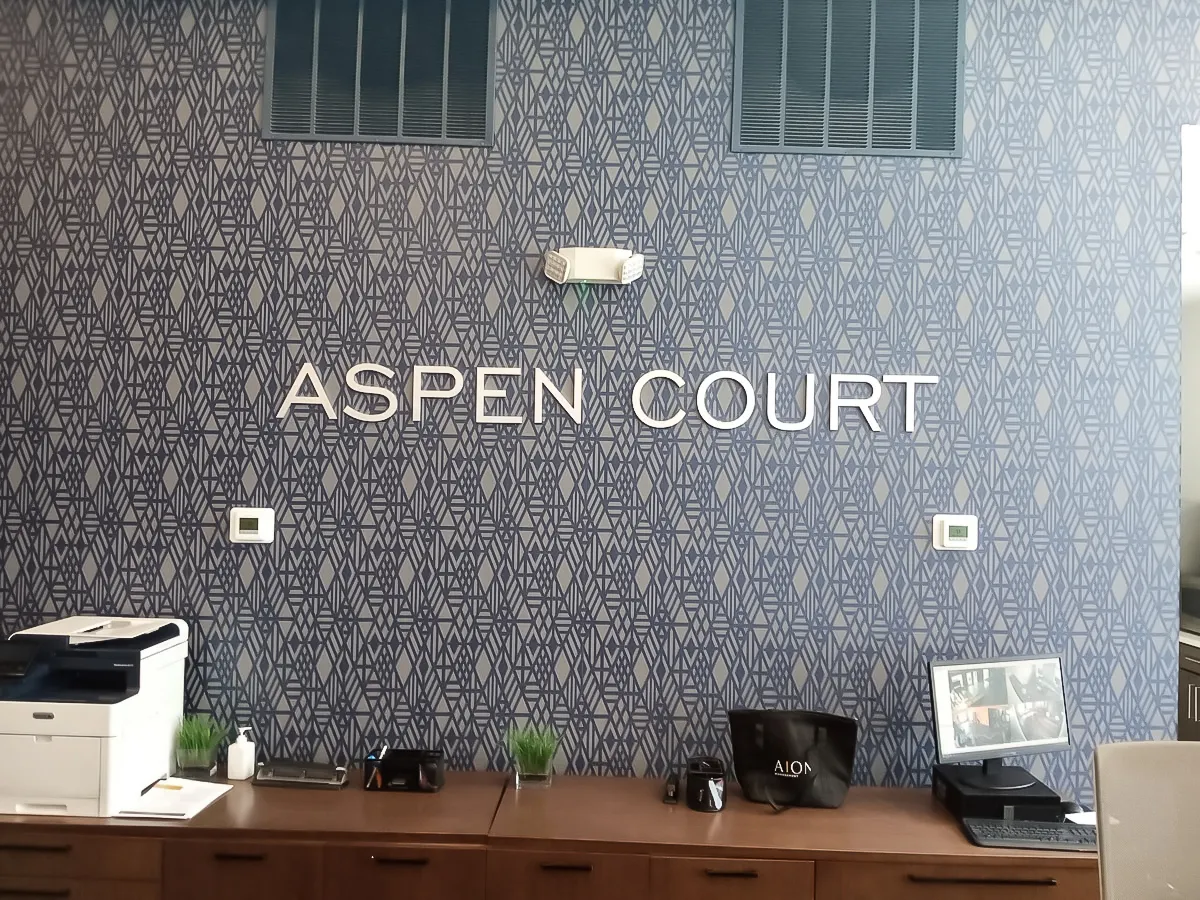 Commercial interior with Aspen Court signage, exterior shades, and office equipment