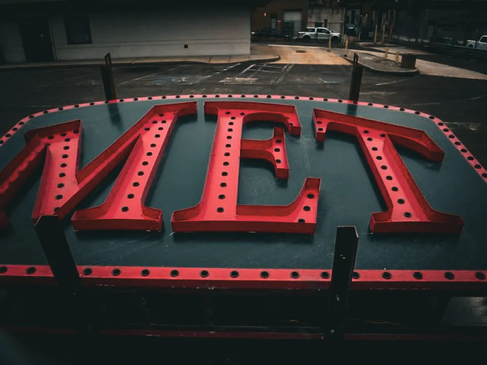 Commercial exterior red MET sign with perforated letters and decorative border