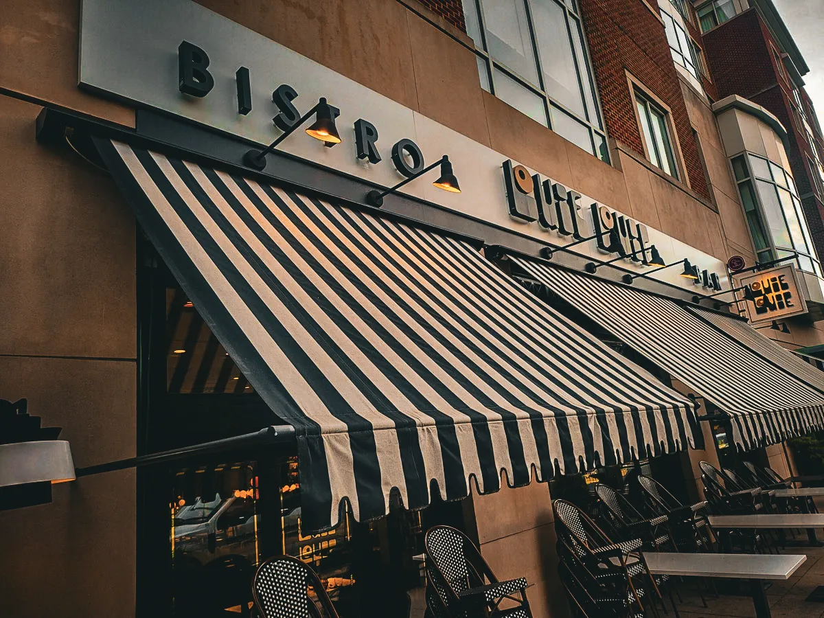 Commercial exterior with bistro signs, awnings, and shades at storefront