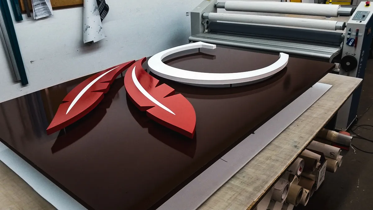 Commercial sign production with red and white exterior signage on printing table